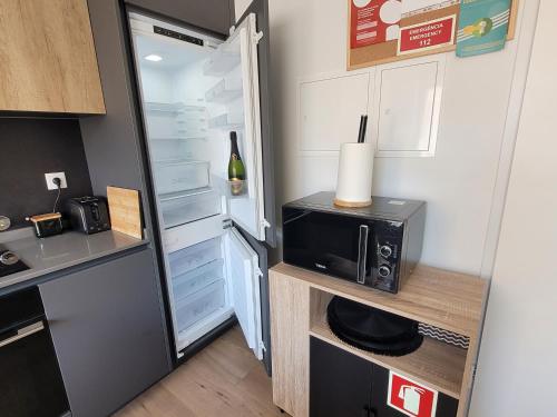 a small kitchen with a refrigerator and a microwave at Moliceiro HOUSE in Aveiro