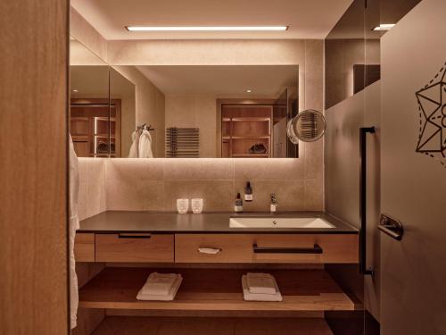 a bathroom with a sink and a mirror at DAS EDELWEISS - Salzburg Mountain Resort in Grossarl