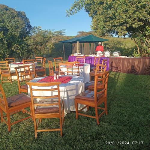a group of tables and chairs with a man in the background at Storms Resort & Campsite in Nanyuki
