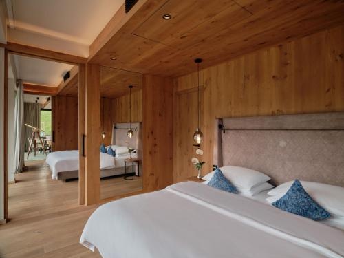 a bedroom with a large white bed and wooden walls at DAS EDELWEISS - Salzburg Mountain Resort in Grossarl