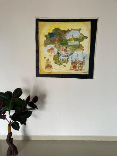 a painting hanging on a wall with a plant at Elysium Inn in Hyderabad