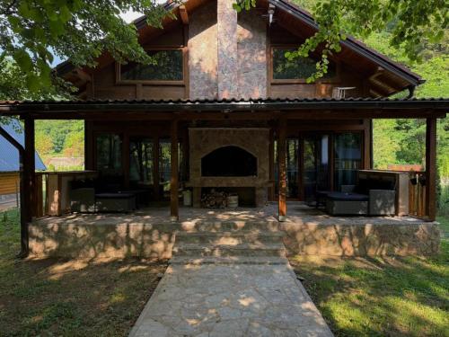 a house with a stone fireplace in the yard at UNA Dream in Ivišovo Greblje