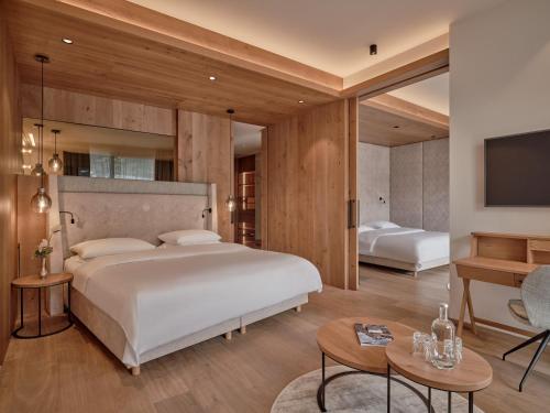 a bedroom with a large white bed and a desk at DAS EDELWEISS - Salzburg Mountain Resort in Grossarl