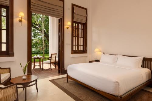 a bedroom with a bed and a table and a chair at Hotel Suisse Kandy - Since 1890 in Kandy