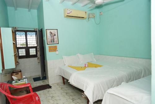 a room with two beds and a red chair at Ranjana Guesthouse in Hampi