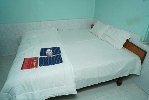 a bed with white sheets and a book on it at Ranjana Guesthouse in Hampi
