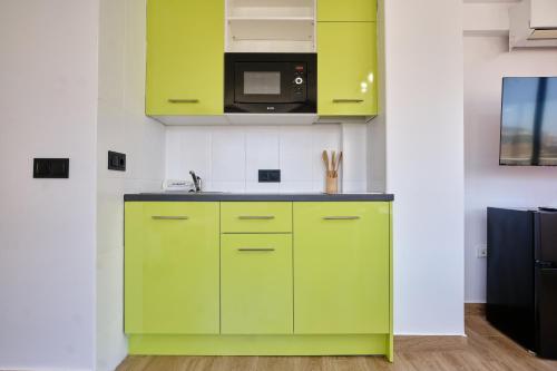 a kitchen with green cabinets and a microwave at Now Benidorm in Benidorm