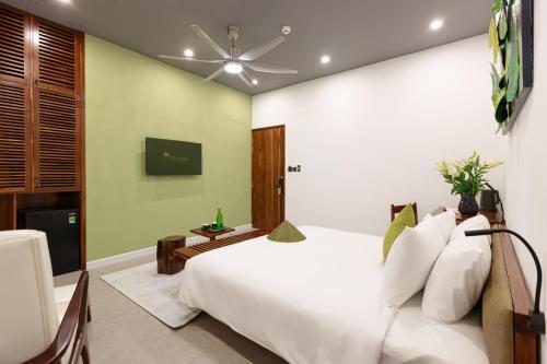a bedroom with a white bed and a ceiling fan at TA Hotel - Hue City Center in Hue
