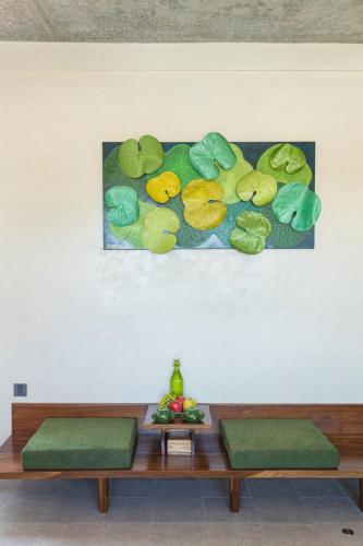 a table with two green benches and a painting of leaves at TA Hotel - Hue City Center in Hue