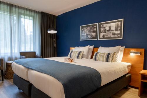 a bedroom with a large bed with blue walls at Landgoed Mennorode in Elspeet