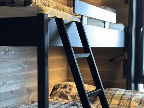 a bunk bed with a ladder next to a bed at Riddergaardens panorama in Beitostøl