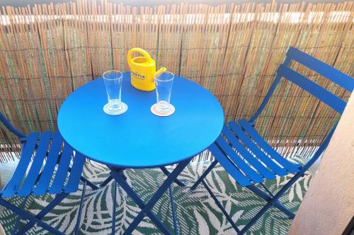 une table bleue avec deux verres et un seau jaune dans l'établissement T2 - Le jardin des fleurs - Sunset, à Sète
