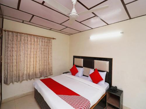 a bedroom with a large bed with red pillows at Hotel O Country Lodge in Dharamshala