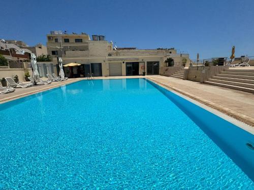 a swimming pool with blue water in front of a building at Sea Breeze Terrace - Marsaskala in Taʼ Monita