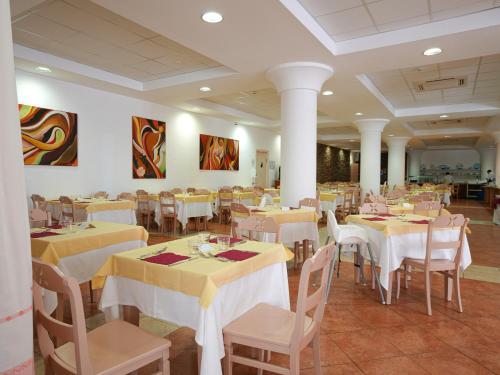 a restaurant with tables and chairs with yellow tablecloths at Hotel La Caletta Village in La Caletta