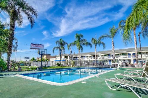 a swimming pool with palm trees in front of a building at Motel 6 Garden Grove in Anaheim