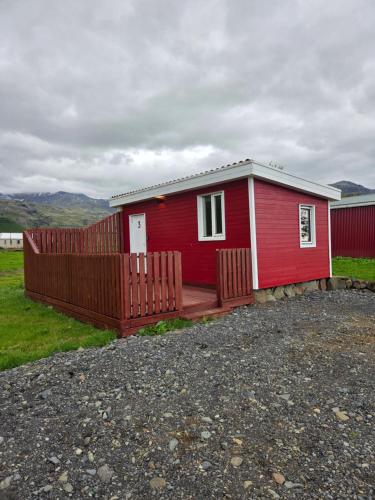 a small red house with a wooden deck at Núpakot in Steinar