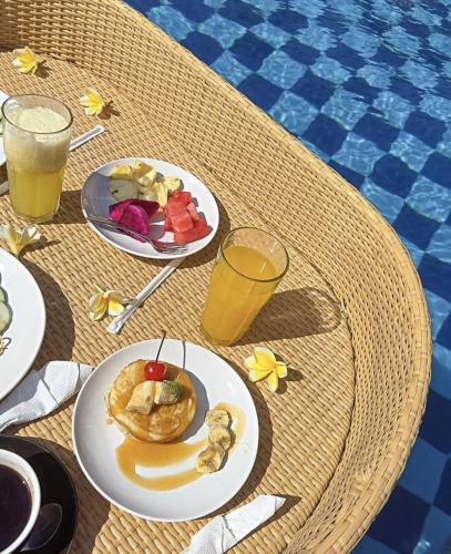 The Kleep Jungle Resort في نوسا بينيدا: طاولة مع أطباق من الطعام والمشروبات بجوار حمام سباحة