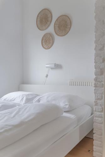 a white bed with two baskets on the wall at - Het Kleine Nest - nabij het meer, strand & Keukenhof in Noordwijkerhout