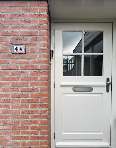 a white door with a sign next to a brick wall at - Het Kleine Nest - nabij het meer, strand & Keukenhof in Noordwijkerhout