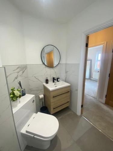 a bathroom with a toilet and a sink and a mirror at 2 bed apartment Moulton Park in Spinney Hill