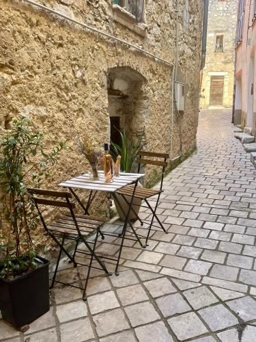 une table et des chaises assises sur une terrasse dans l'établissement Appartement cosy dans le centre historique de Vence, à Vence