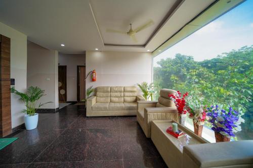 a living room with a couch and a large window at Open Hotel by Olive - The Emerald Inn in Bengaluru