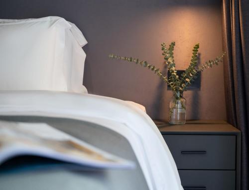 a vase with a plant on a table next to a bed at Banana Fun Hotel - Guangzhou East Railway Station Yantang Metro Station in Guangzhou