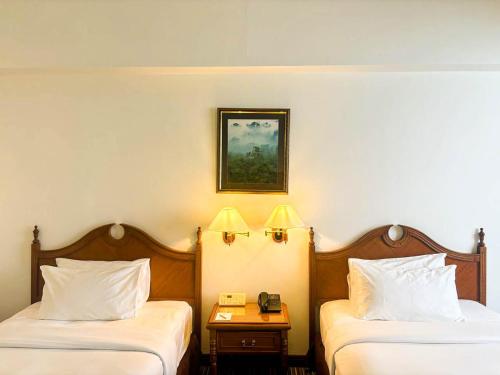 a hotel room with two beds and a phone on a table at Mulia Hotel in Bandar Seri Begawan