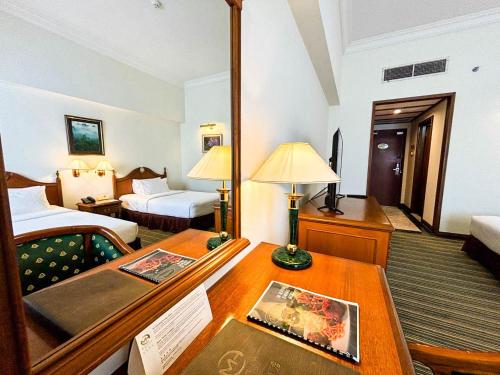 a hotel room with a bed and a desk and a room at Mulia Hotel in Bandar Seri Begawan