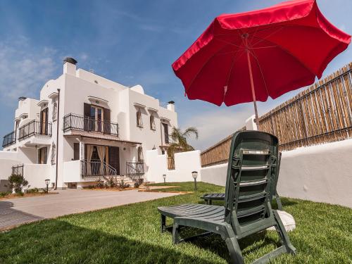 a red umbrella and a chair in front of a house at Villa Omero in Sperlonga