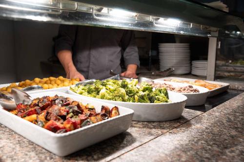 a kitchen with three trays of food on a counter at Hotel La Caletta Village in La Caletta