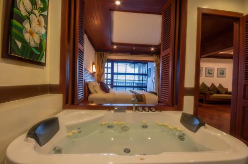 a large bath tub in a room with a bedroom at Borei Angkor Resort & Spa in Siem Reap