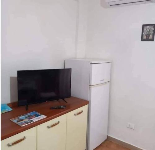 a kitchen with a white refrigerator and a television at La Casa di Anna in Lampedusa