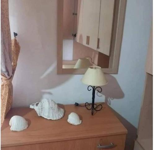 a lamp on top of a dresser with a mirror at La Casa di Anna in Lampedusa