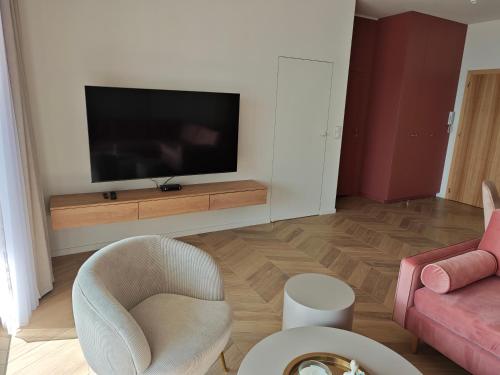 a living room with a tv and a couch and a chair at Apartament 31 in Boszkowo-Letnisko