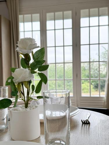 - une table avec un vase et des fleurs blanches dans l'établissement Studio Platanes 2 - Proche Disneyland - Parking Gratuit - Meaux, à Meaux