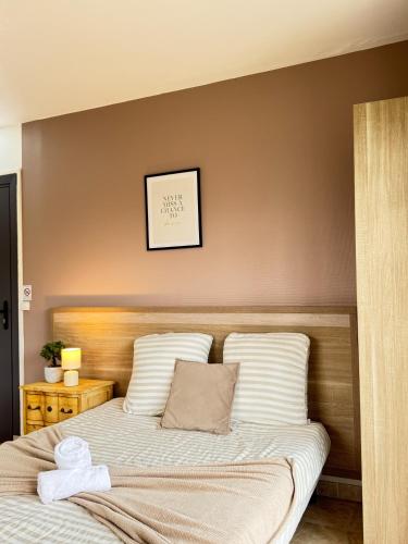 - un lit avec des oreillers blancs et une horloge murale dans l'établissement Studio Platanes 2 - Proche Disneyland - Parking Gratuit - Meaux, à Meaux