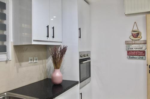 una cocina con armarios blancos y un jarrón en una encimera en Luxury varkiza apartment, en Vari