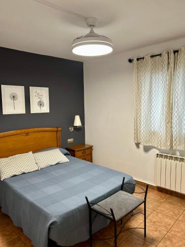 a bedroom with a blue bed and a chair at La Calleja in Hervás