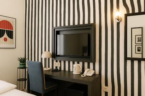 a room with a desk with a television on a striped wall at Hotel Ottofiori in Budapest