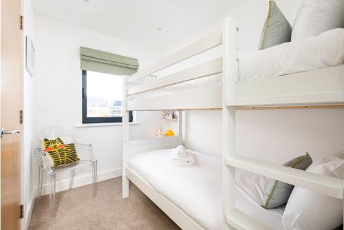 a bedroom with white bunk beds and a chair at Sunday Sun BR31 Silverlake Dorset in Warmwell