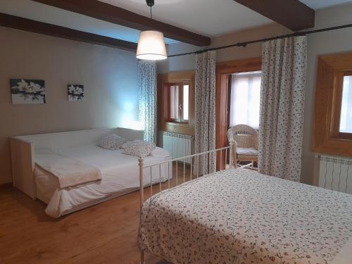 a bedroom with two beds and two windows at Casa Cotiellu in Llanes