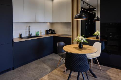 ジェシュフにあるApartament Niebieski Horyzont Kopisto 11 Centrum Miasta Rzeszówのテーブルと椅子のあるキッチンと白いキャビネットのあるキッチン