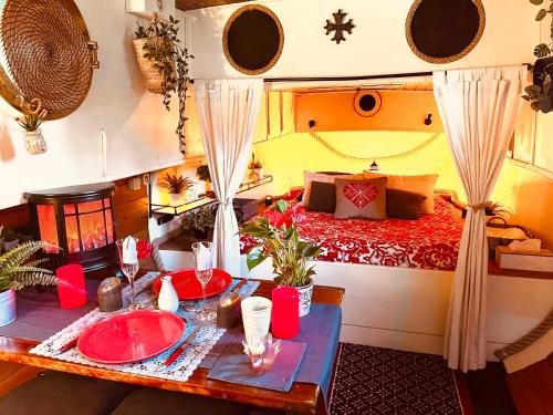 une chambre avec un lit et une table avec des assiettes rouges dans l'établissement Très jolie péniche à louer, à Hédé