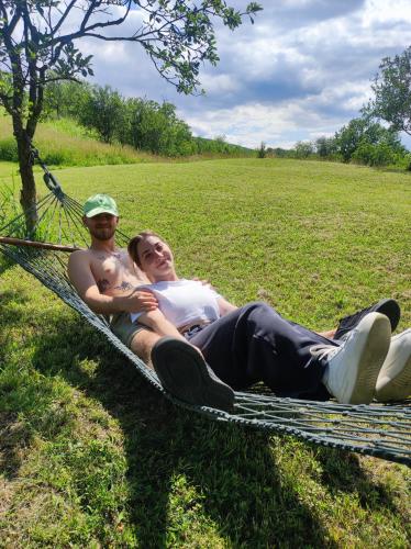 a man and woman laying on a hammock in a field at ZEN Apartments in Măgura