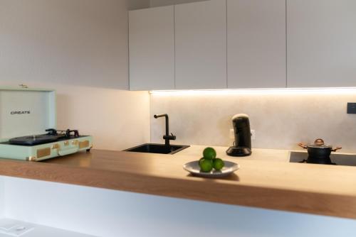 a kitchen with a sink and a bowl of fruit on a counter at Velotique Hotel Angelika - Self-Check-in in Hard