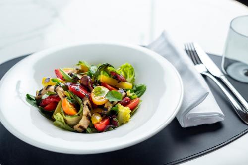 a white plate with a salad on a table at Hilton Turin Centre in Turin