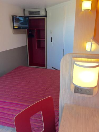 a small room with a bed and a table and a light at Premiere Classe Montpellier Ouest - St Jean De Vedas in Saint-Jean-de-Védas