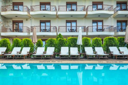 a row of chairs and umbrellas next to a swimming pool at Nereides Hotel in Hanioti
